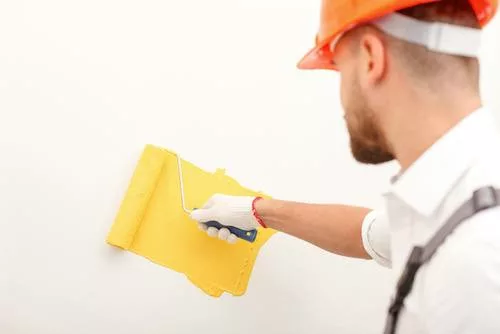 Man painting wall yellow