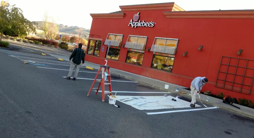 Timmins painting employees painting Applebee's parking spots