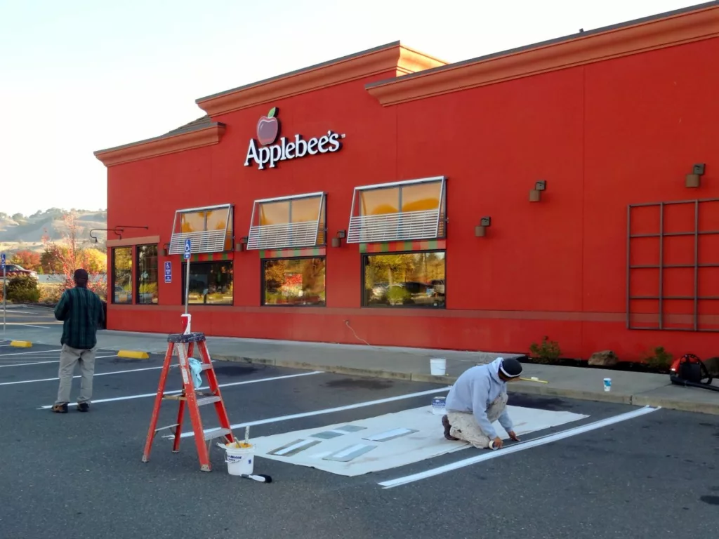 Timmins painting employees painting Applebee's parking spots