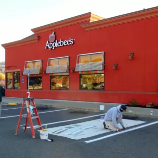 Timmins painting employees painting Applebee's parking spots