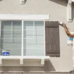 Busy House Painter Painting the Trim And Shutters of A Home.