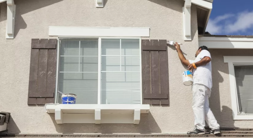 Busy House Painter Painting the Trim And Shutters of A Home.