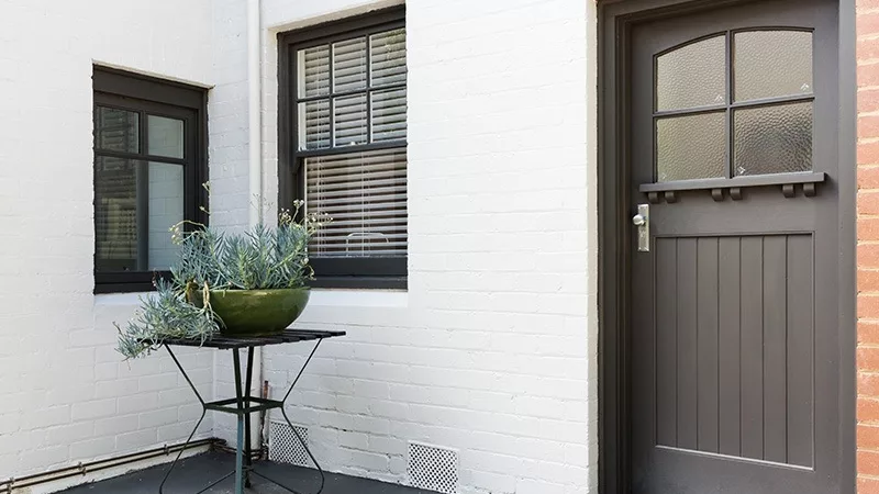 the front porch of a brick house painted white