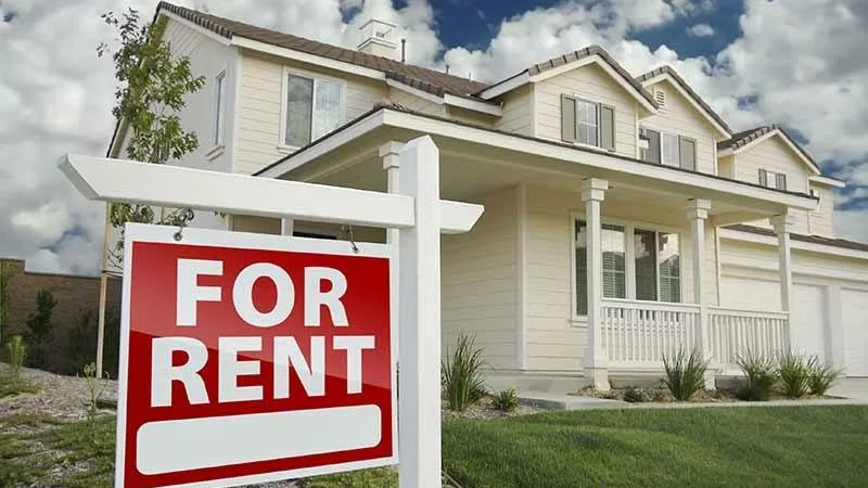 freshly painted house with a for rent sign out front