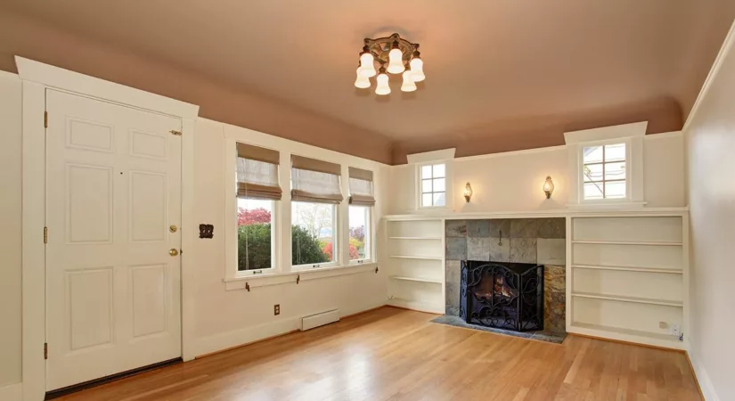 empty living room with white walls and dusky rose ceiling, and sunlight streaming through windows onto hardwood floors.