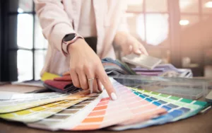 Arm and hand of woman in business blazer pointing to color on fan of swatches