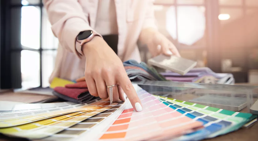 Arm and hand of woman in business blazer pointing to color on fan of swatches