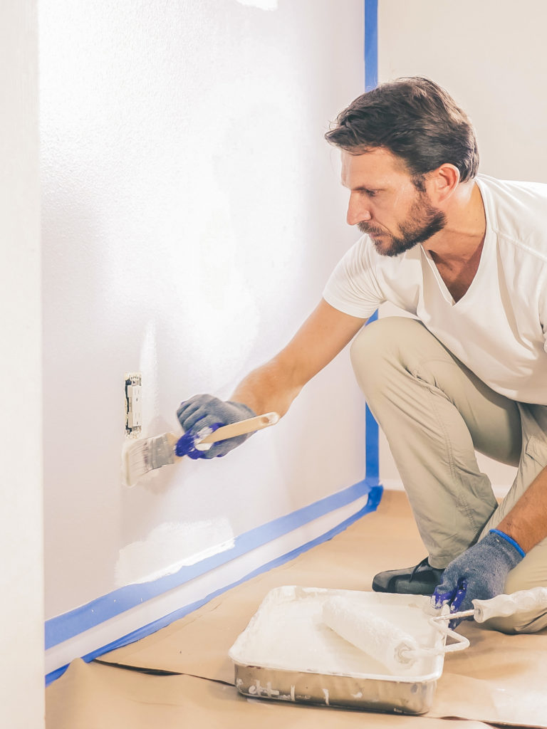 man painting a wall with a paint brush