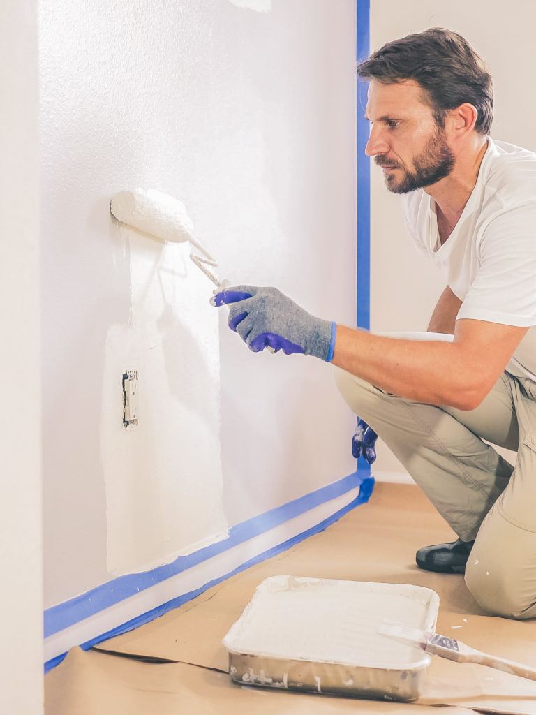 man painting a wall with a paint roller