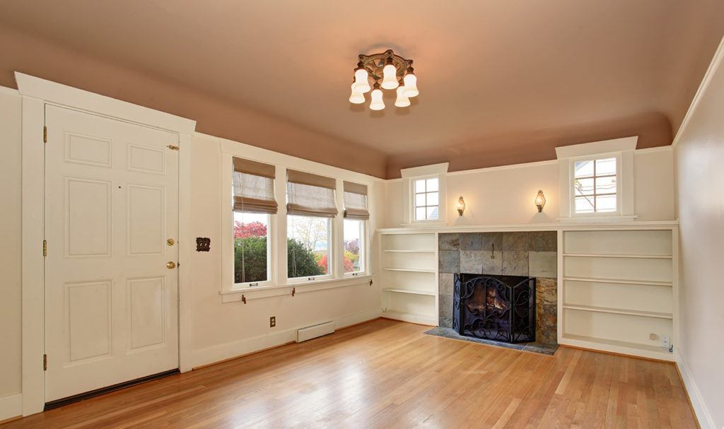 empty room with white woodwork, hardwood floors and wam-colored ceiling