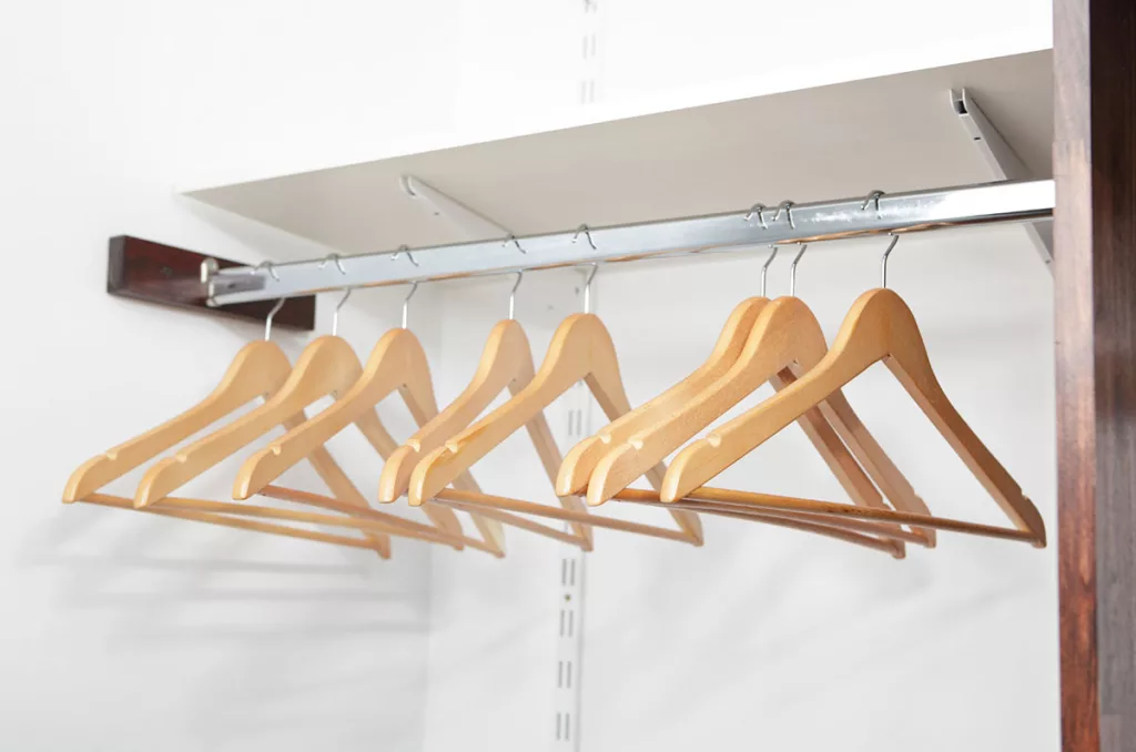 An empty closet with wooden clothes hangers is prepped for professional residential painting.