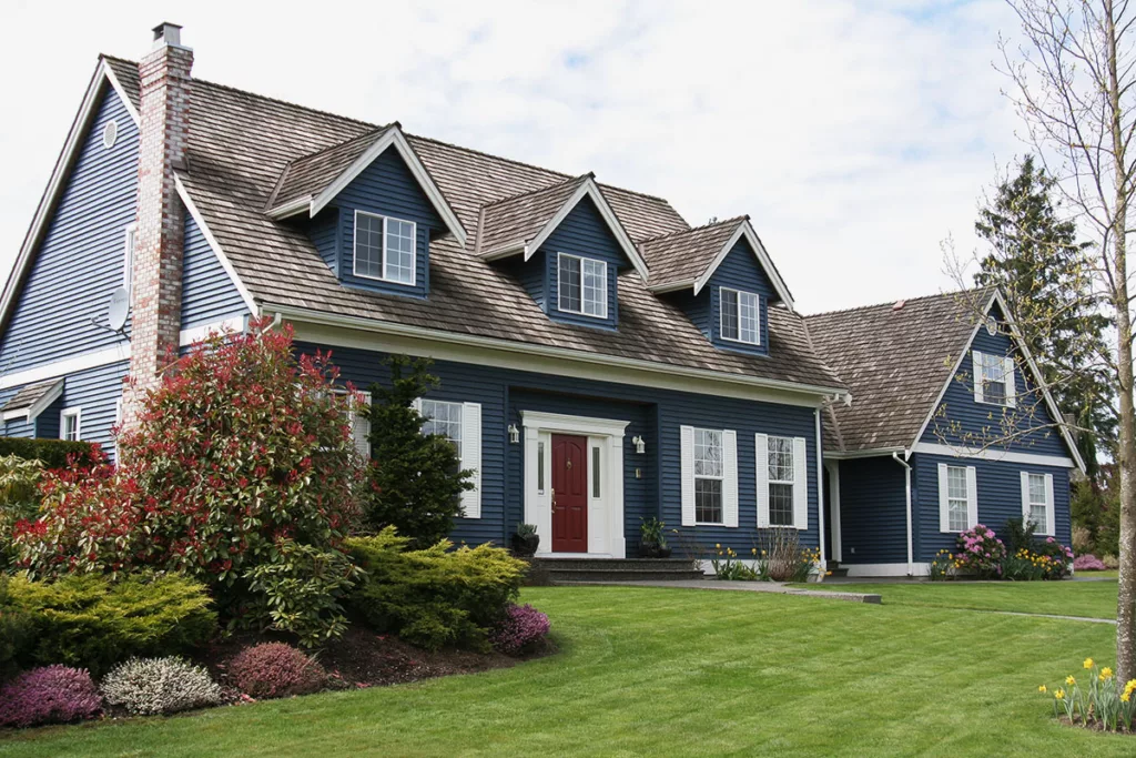 A house with dark blue exterior paint, a red door, and a large front lawn