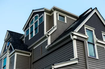 The exterior of a large historic house with dark gray exterior paint