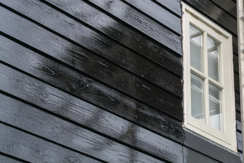 The exterior of a house has just been painted with a fresh coat of dark black exterior paint