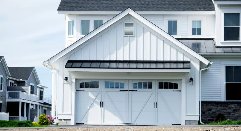 A two-story house with a fresh coat of white exterior paint and two garages