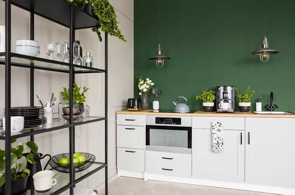 A clean kitchen with white cabinets and walls painted dark green.
