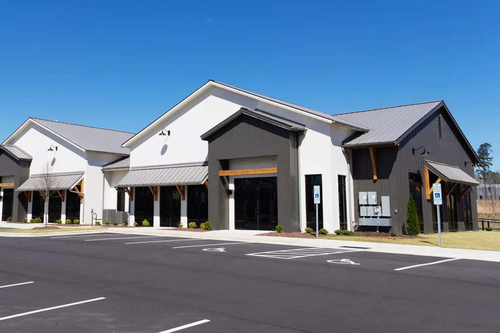 The exterior of a professionally painted commercial building with white and black paint and wood accents, and an empty parking lot