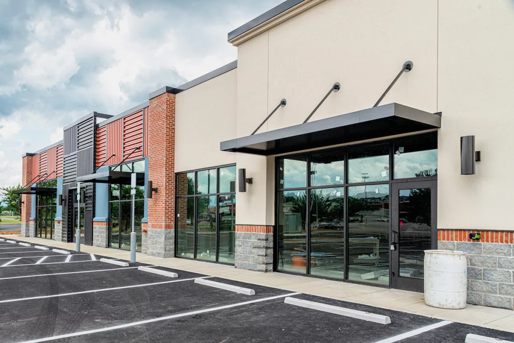 The exterior of a professionally painted strip shopping center with beige and brick commercial buildings