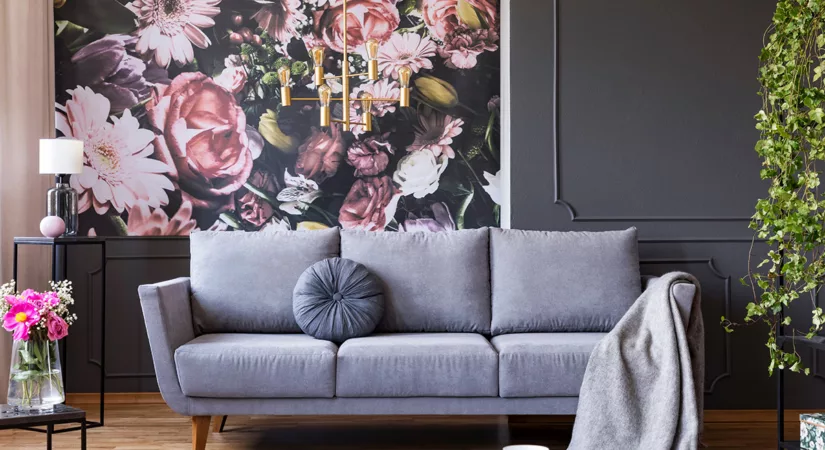 The interior of a living room, with half of the wall covered in dark floral wallpaper, and the other painted black.