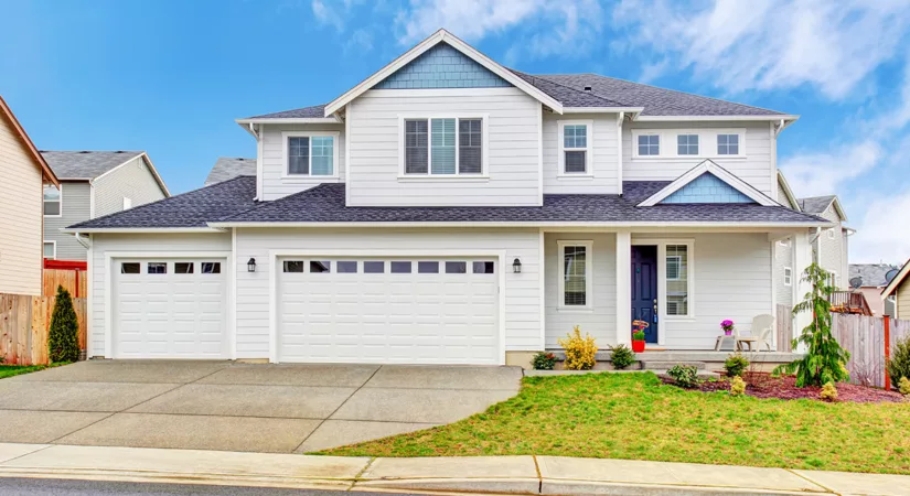 A two level house with white exterior paint and a green front lawn