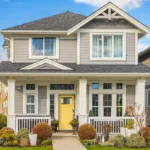A newly painted home exterior with beige paint and a yellow door