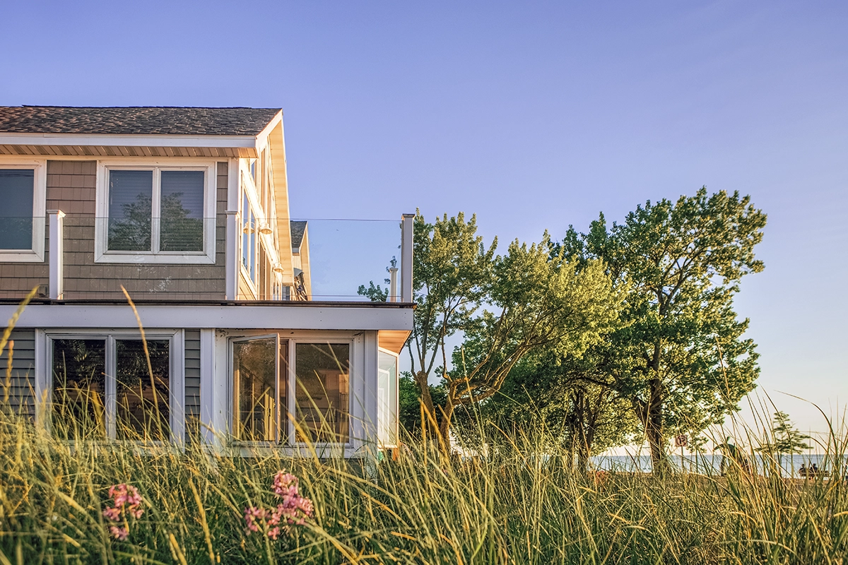A coastal home with grass and a tree and a new coat of exterior paint